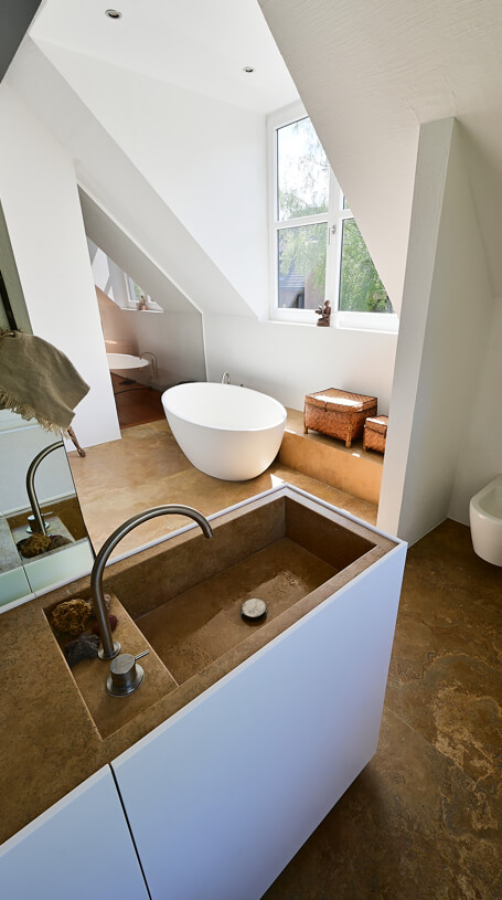 persönliche Badgestaltung mit weißen Wänden und hellbraunem Naturstein für Waschbecken und Bodenplatten
