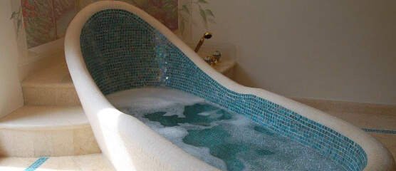 Baden Sie umgeben von Mosaik aus Glas und Naturstein - eine Badgestaltung mit besonderer Badewanne, die zu anmutigen Lichtspielen und zu Ihrer Entspannung führt.